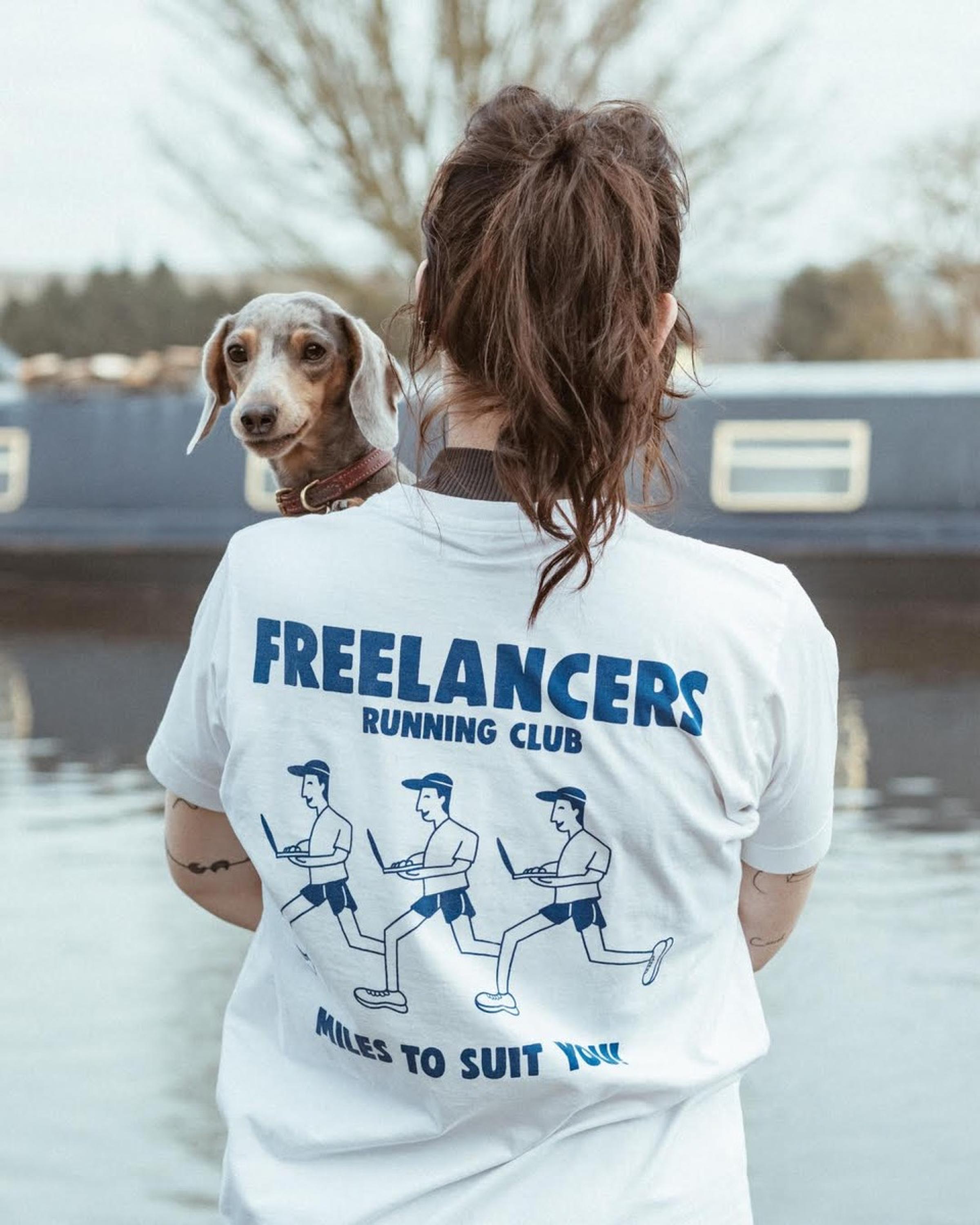 Woman in a running t-shirt from freelancers running club holding a dog